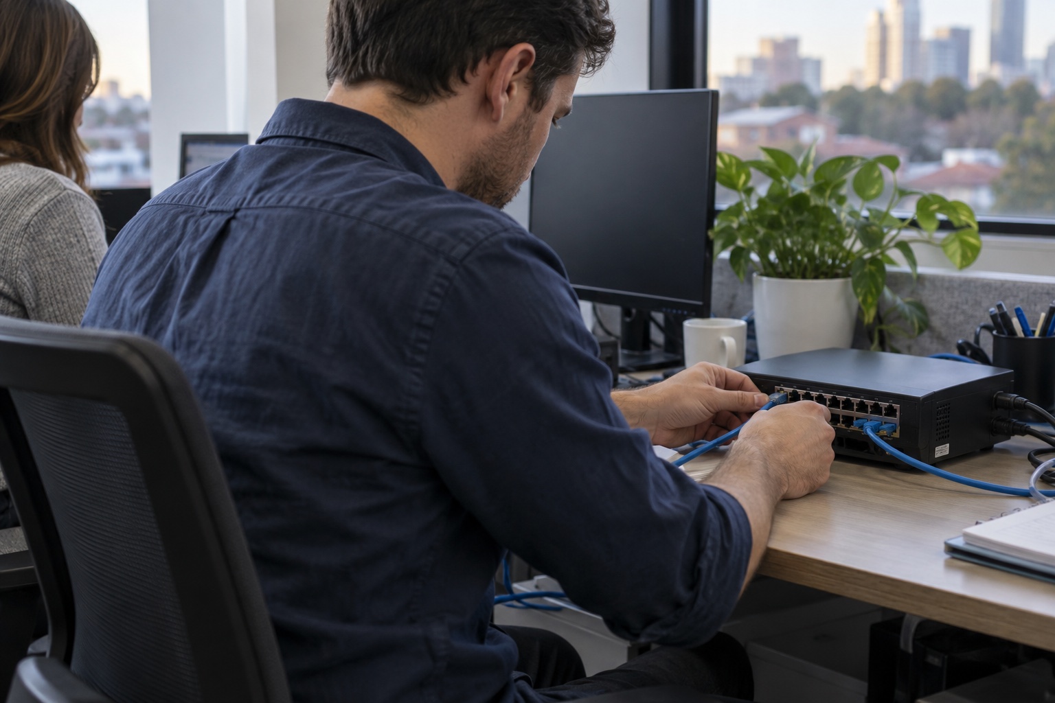 Illustrative photograph of hands connecting office network equipment